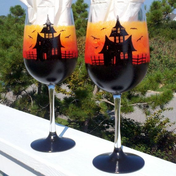 two wine glasses sitting on top of a wooden table next to each other with halloween decorations painted on them