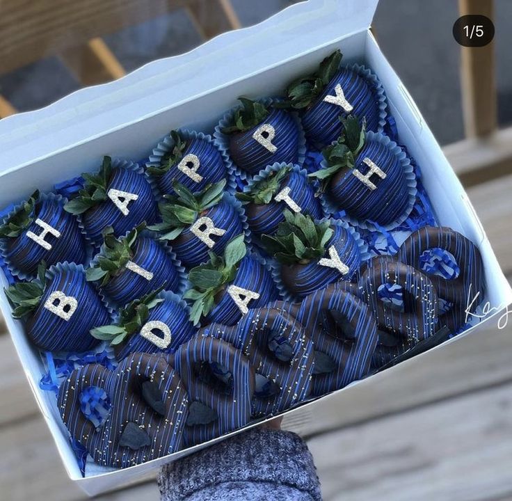 a person holding up a box of chocolates with the words happy birthday written on them