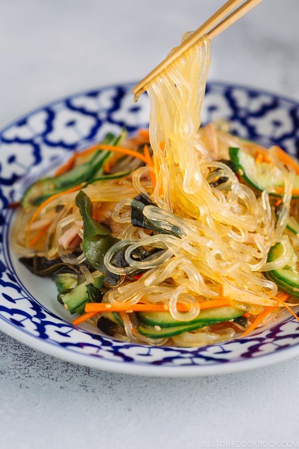 a blue and white plate topped with noodles and veggies