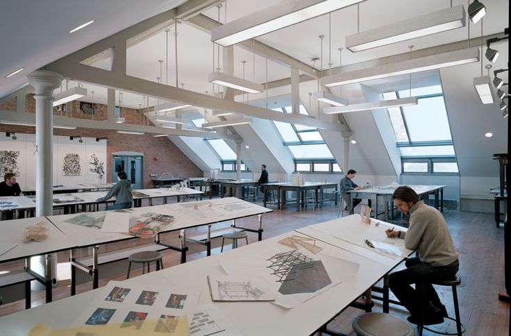 a man sitting at a table in an open room with lots of papers on it