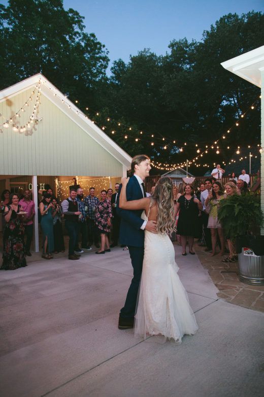 a bride and groom share their first dance as guests look on in the background at night