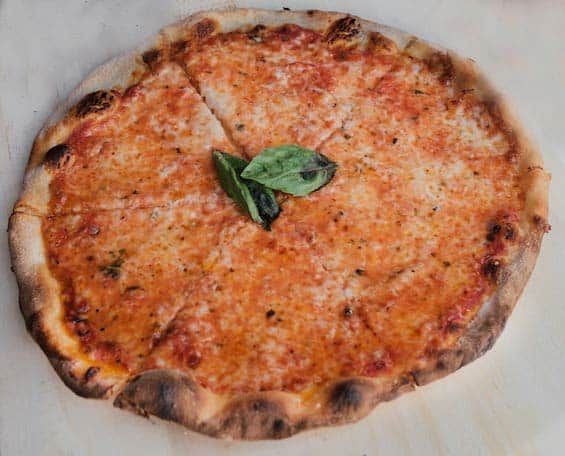 a cheese pizza with basil leaves on top