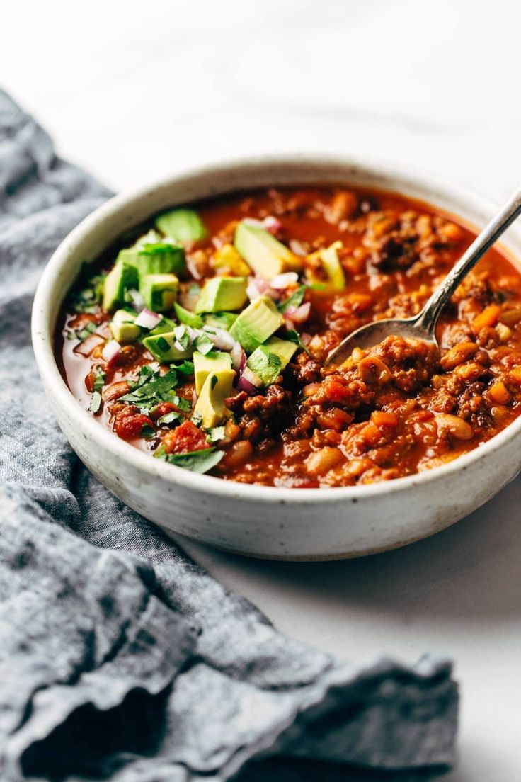 a white bowl filled with chili and avocado