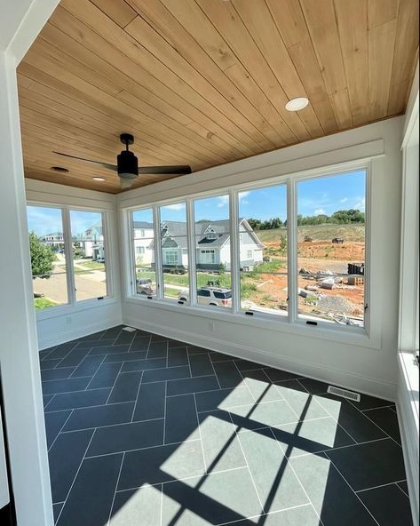 an empty room with large windows and tile flooring