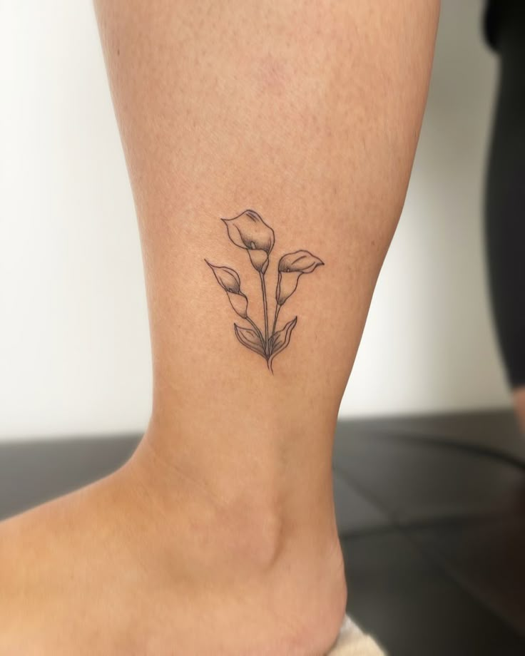 a woman's foot with a small flower tattoo on the back of her leg