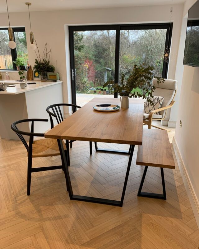 a dining room table with chairs and a bench in front of the sliding glass doors