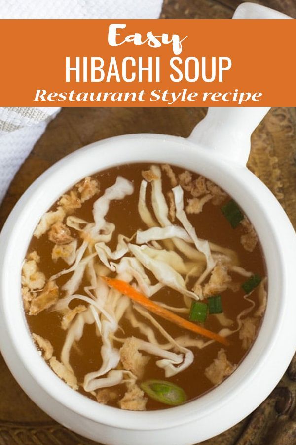 a bowl of soup with noodles and carrots in it on a wooden table next to a napkin