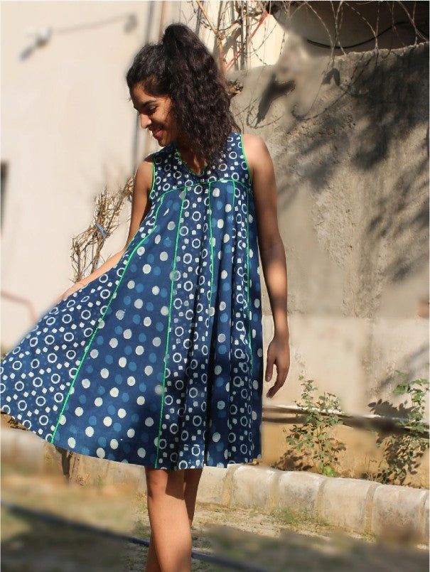 Twirl around in this indigo kali dress with a contrasting border on the inner hem. Quirky hand block print with bright trims and back tie up dori with poms poms makes it a perfect dress for a fun day out. Bright colorful pom poms on back neck string pockets for comfort unique, hand block motifs created by Indian artisans Color: Blue Fabric: 100% Cotton Note: The product will be delivered within 2-4 weeks of order placed Wash Care - Dry clean only Variation in yarn, weave & color are unique & int Sleeveless Cotton Dress With Batik Print, Blue Batik Print Sleeveless Dress, Blue Sleeveless Batik Print Dress, Blue Sleeveless Dress With Batik Print, Blue Bohemian Bandhani Print Dress, Blue Bohemian Dress With Bandhani Print, Traditional Blue Cotton Dress, Summer Indigo Ikat Print Dresses, Traditional Bandhani Print Summer Dress