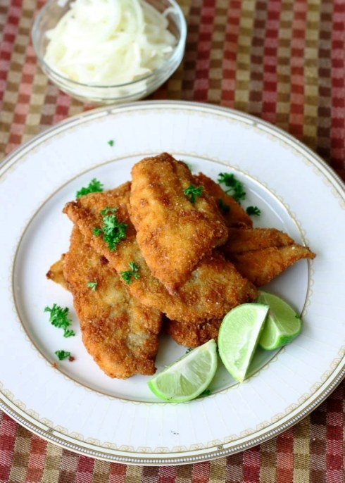 some food is on a white plate with lime wedges and sour kraut