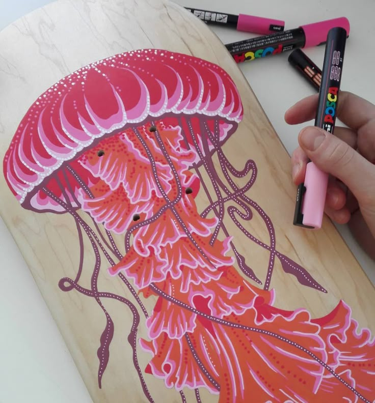 a person is drawing on a piece of wood with markers and crayon pens