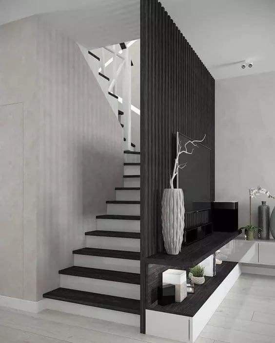 there is a black and white stair case in the living room with vases on it