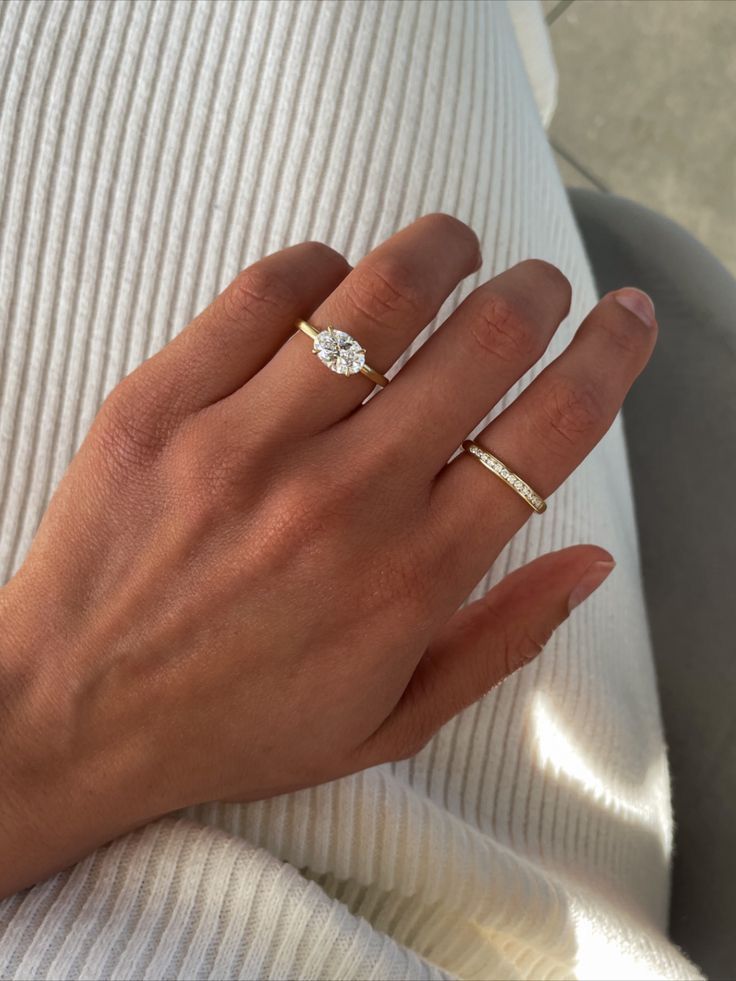 a woman's hand with two gold rings on her left and one diamond ring on her right