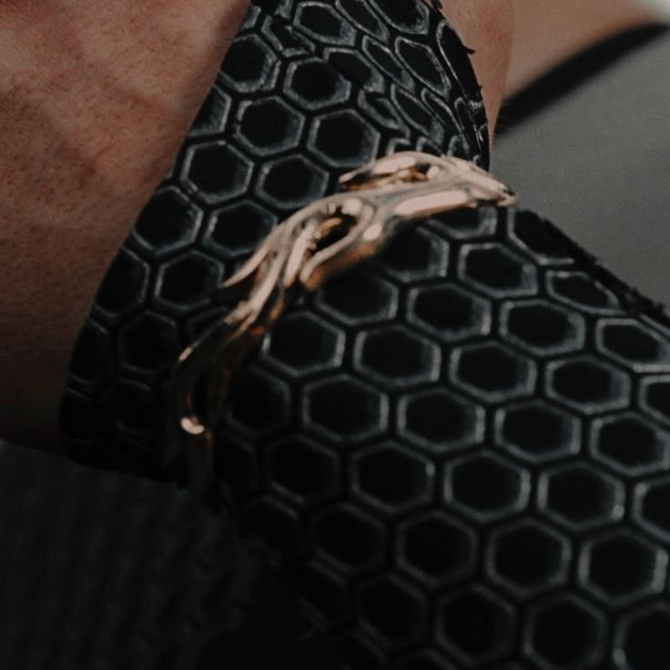 a close up of a person wearing a black tie with gold chains on his arm