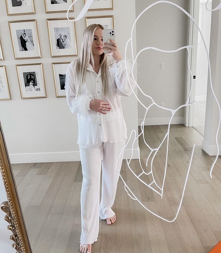 a woman standing in front of a mirror taking a selfie with her cell phone