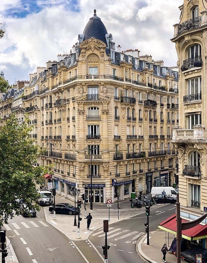 an old building is on the corner of a street in paris, with cars driving by