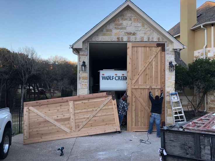 two men are working on the side of a house that is being built with wood