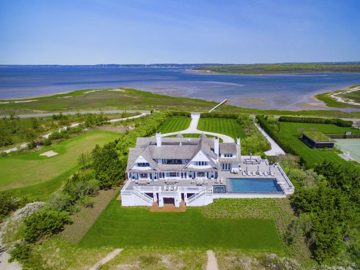 an aerial view of a large white house with a pool in the middle of it