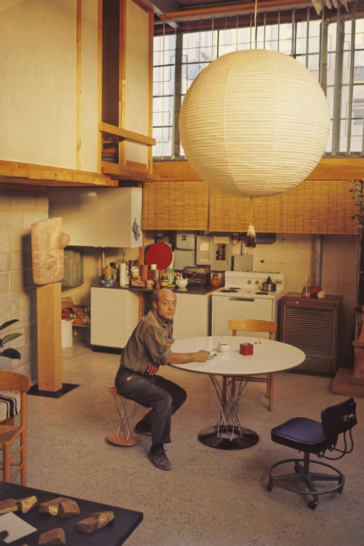 a man sitting at a table in a room with lots of furniture and decor on the walls