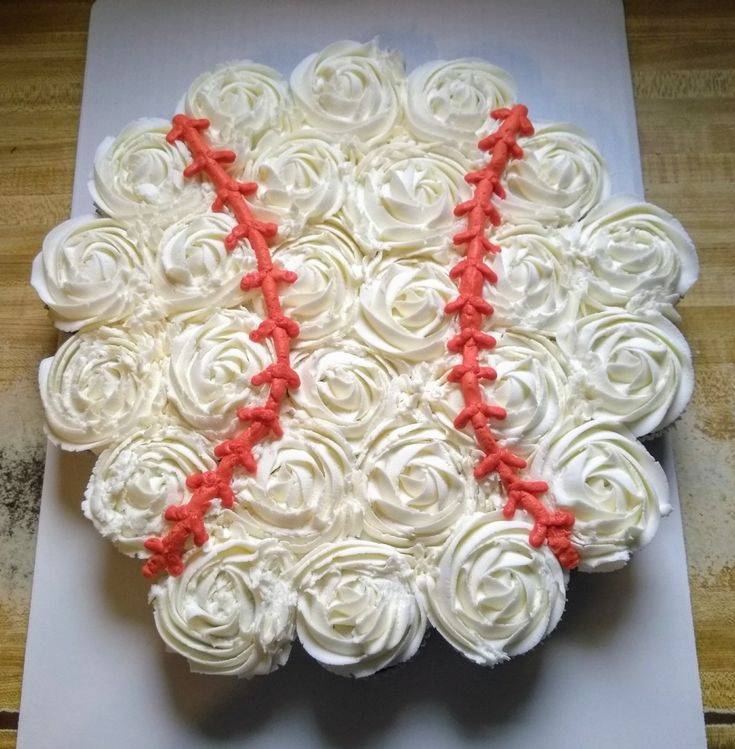 a baseball cake with white frosting and red piping on the top is sitting on a cutting board