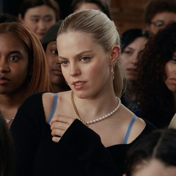 a group of women standing next to each other in front of a crowd with one woman looking at the camera