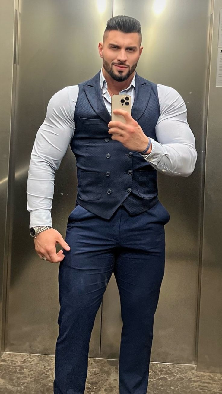 a man taking a selfie in front of an elevator door wearing a blue suit and white shirt