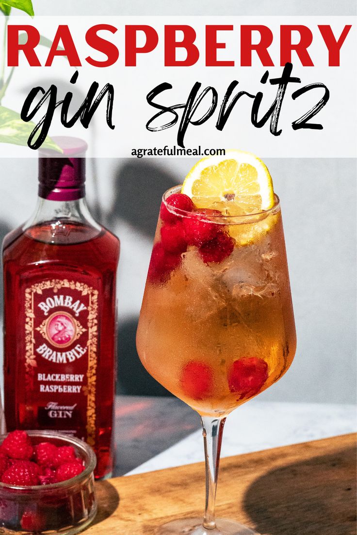 raspberry gin spritz in a glass next to a bottle of gin