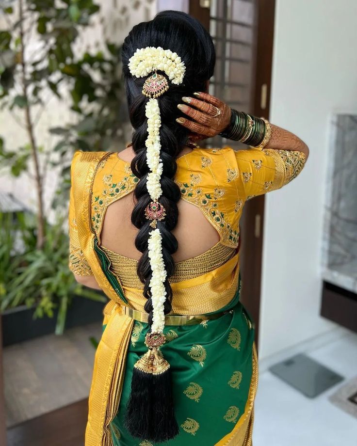 a woman in a yellow and green sari is holding her hair up to the side