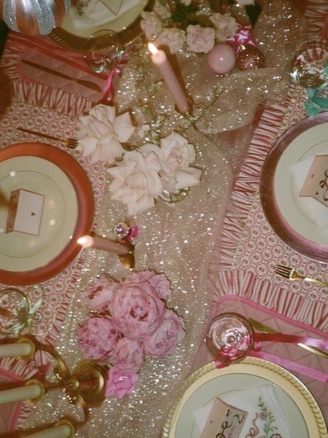 the table is set with pink and white plates, silverware, and napkins