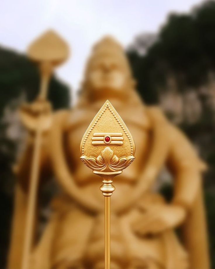 a golden statue with a red stone in the center and a gold stick sticking out of it