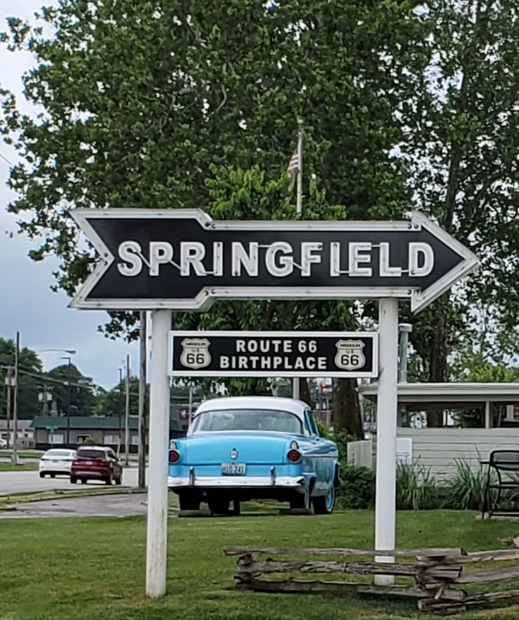 a street sign that says springfield in front of a blue car and picnic table