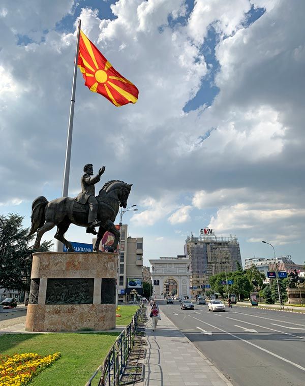 a statue of a man riding a horse next to a flag on top of a pole