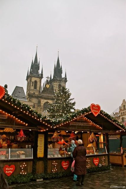 people standing in front of a christmas market with lights and decorations on the outside wall