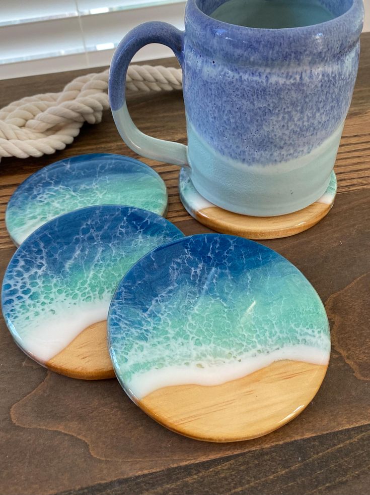 three blue and white ceramic coasters next to a coffee cup on a wooden table