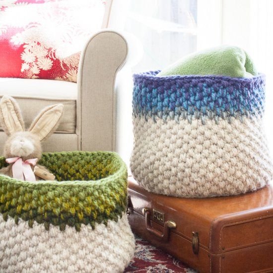 two knitted baskets sitting next to each other on top of a rug in front of a chair