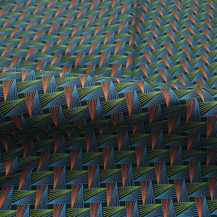 a blue and green patterned fabric with an orange design on the bottom half of it