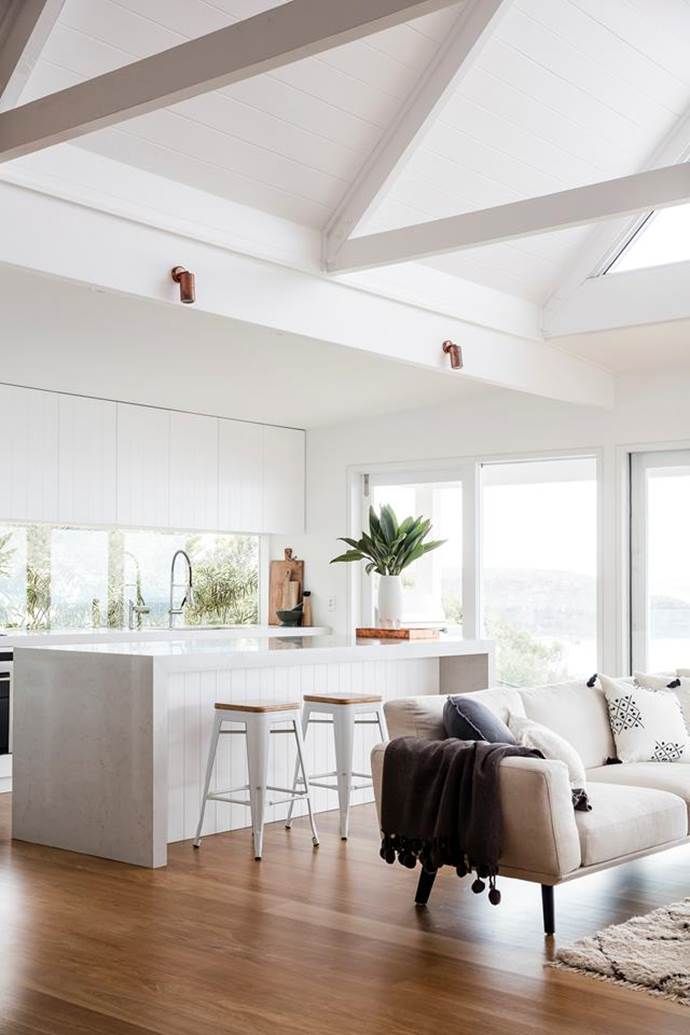 a living room filled with furniture next to a kitchen and an island in front of a window