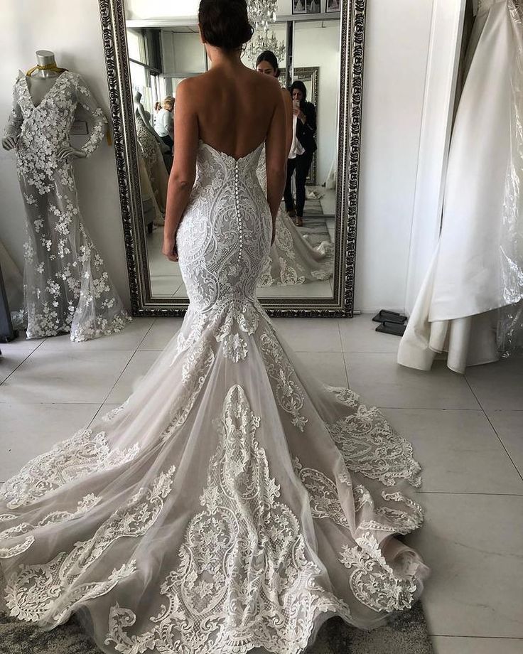 a woman is looking at her wedding dress in front of a mirror and mannequins