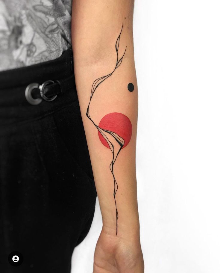 a woman's arm with a red and black tattoo design on the left forearm