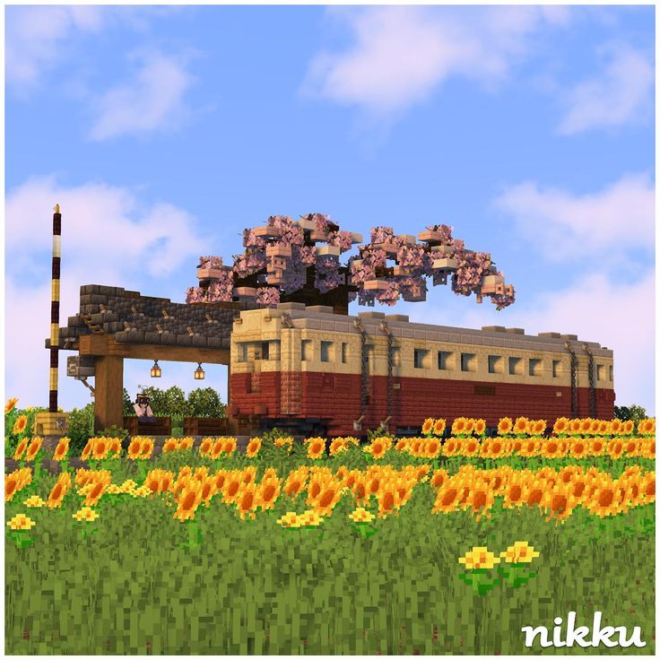 a train traveling through a lush green countryside next to tall yellow sunflowers in front of a blue sky