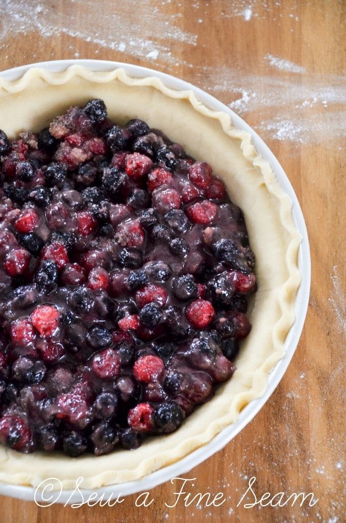 a pie crust filled with blueberries on top of a wooden table