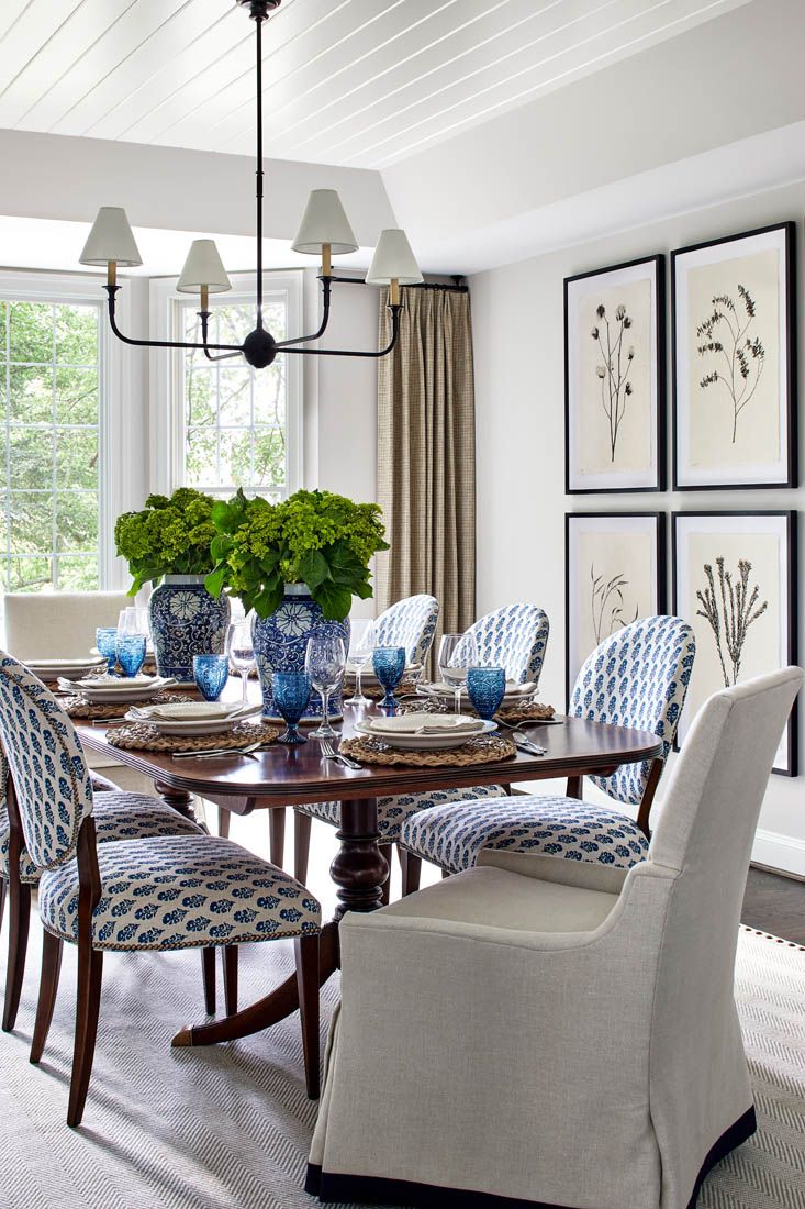 a dining room table with blue and white chairs in front of a chandelier