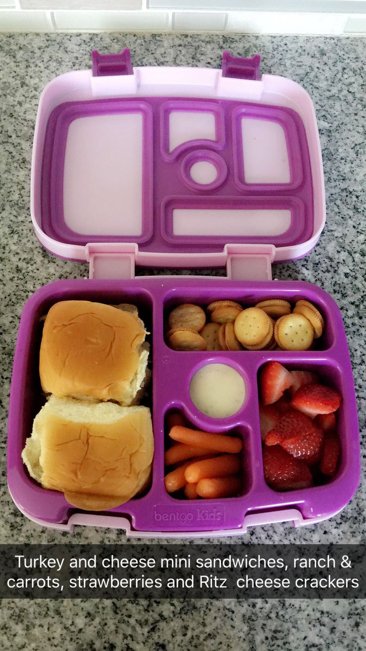 a purple lunch box filled with sandwiches and fruit