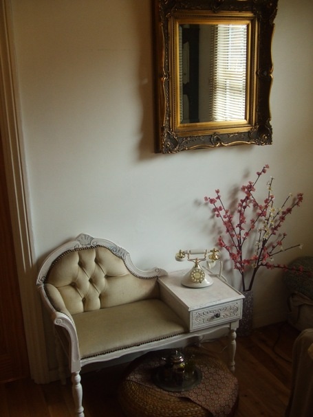 a room with a couch, table and mirror on the wall next to a chair