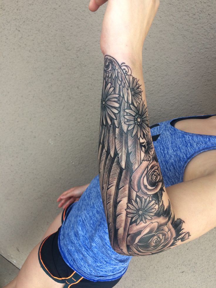 a woman's arm with an angel tattoo on it and flowers in the background