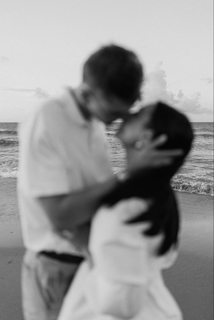 a man and woman kissing on the beach