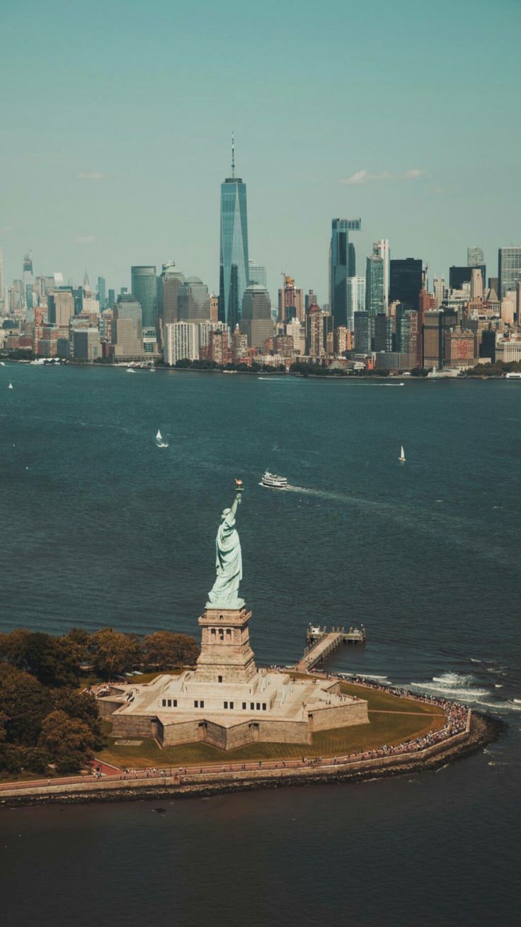 an aerial view of the statue of liberty in new york city, with manhattan in the background