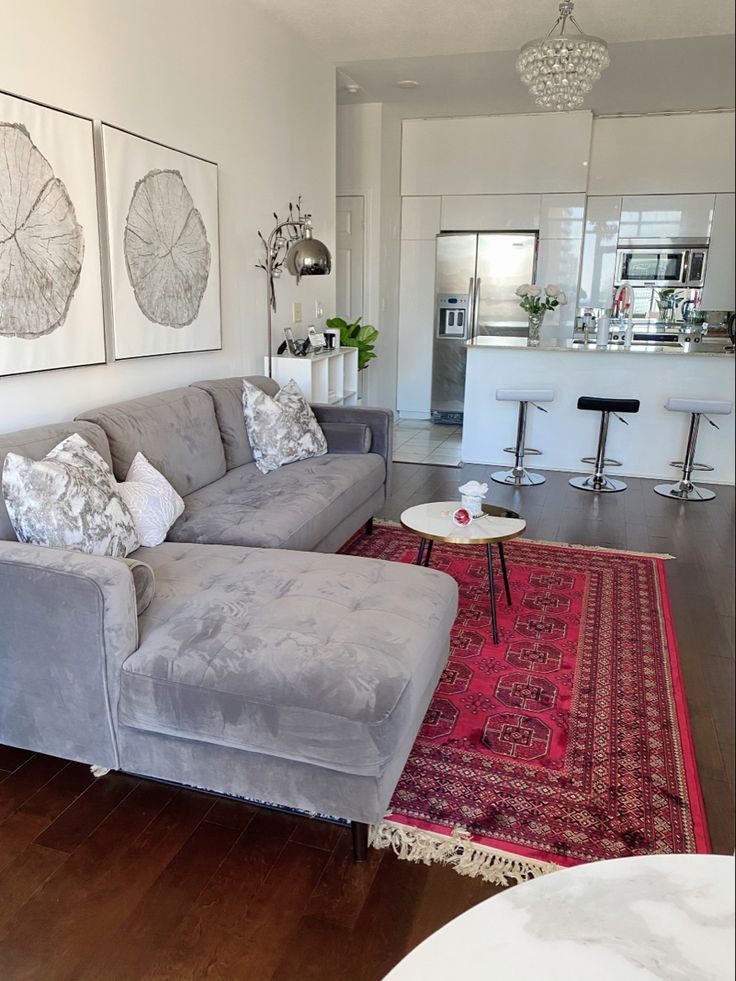 a living room filled with furniture next to a red rug on top of a hard wood floor