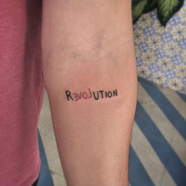 a person with a tattoo on their arm that says revolution above the word revolution in cursive font