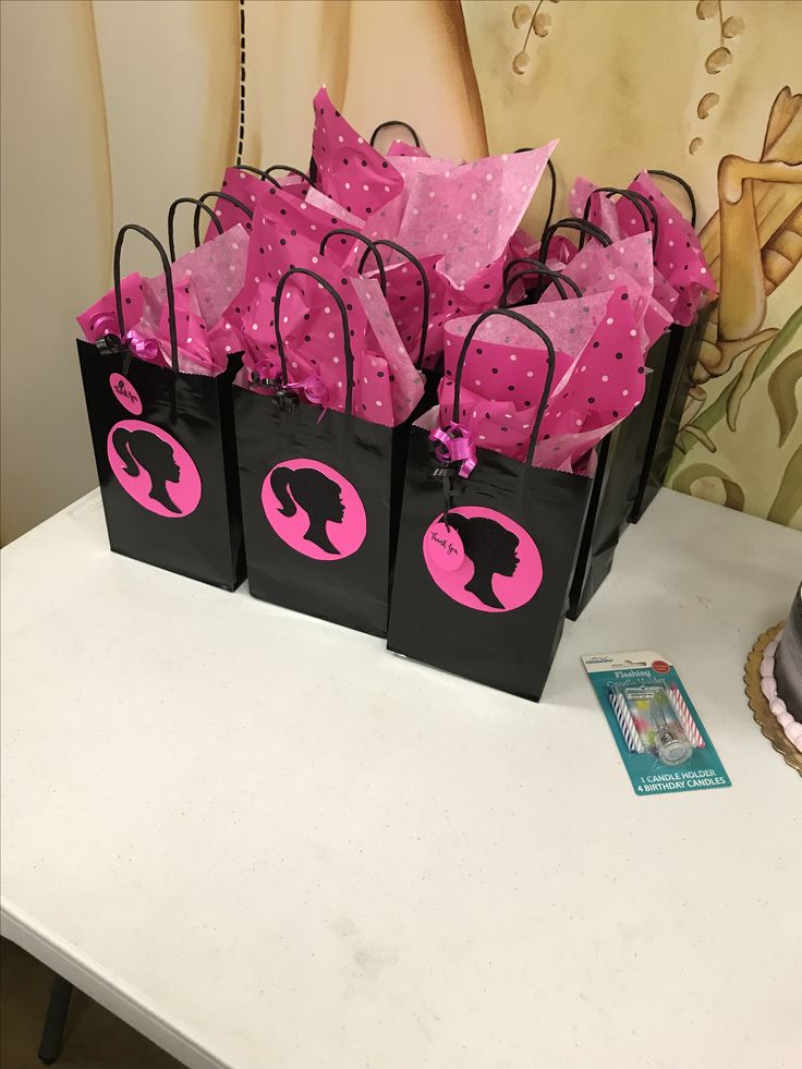 pink and black gift bags with silhouettes on them sitting on a table next to a cupcake