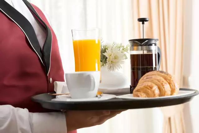 a waitress holding a tray with coffee, croissants and orange juice on it